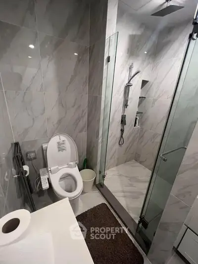 Modern bathroom with marble tiles, glass shower, and sleek fixtures.