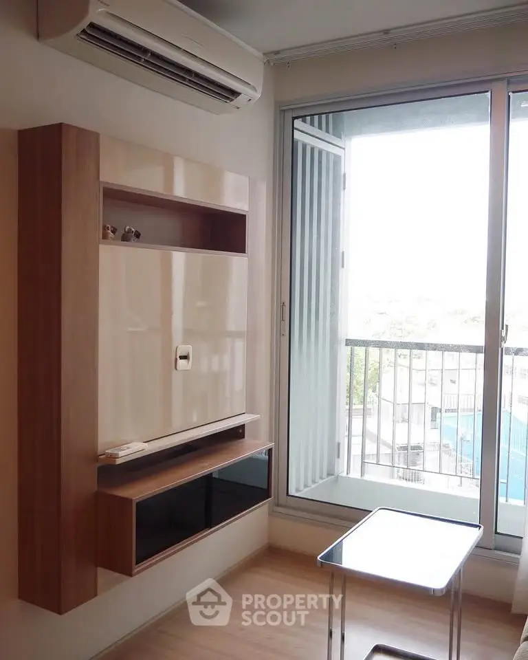 Modern living room with air conditioning and balcony view, featuring sleek wall-mounted storage and glass table.