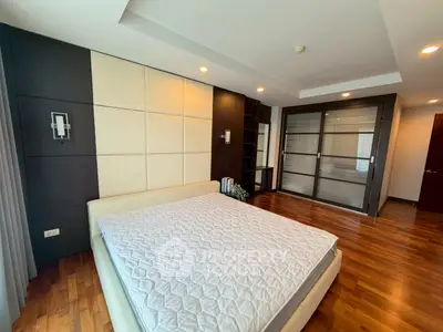 Spacious modern bedroom with wooden flooring and stylish built-in wardrobe