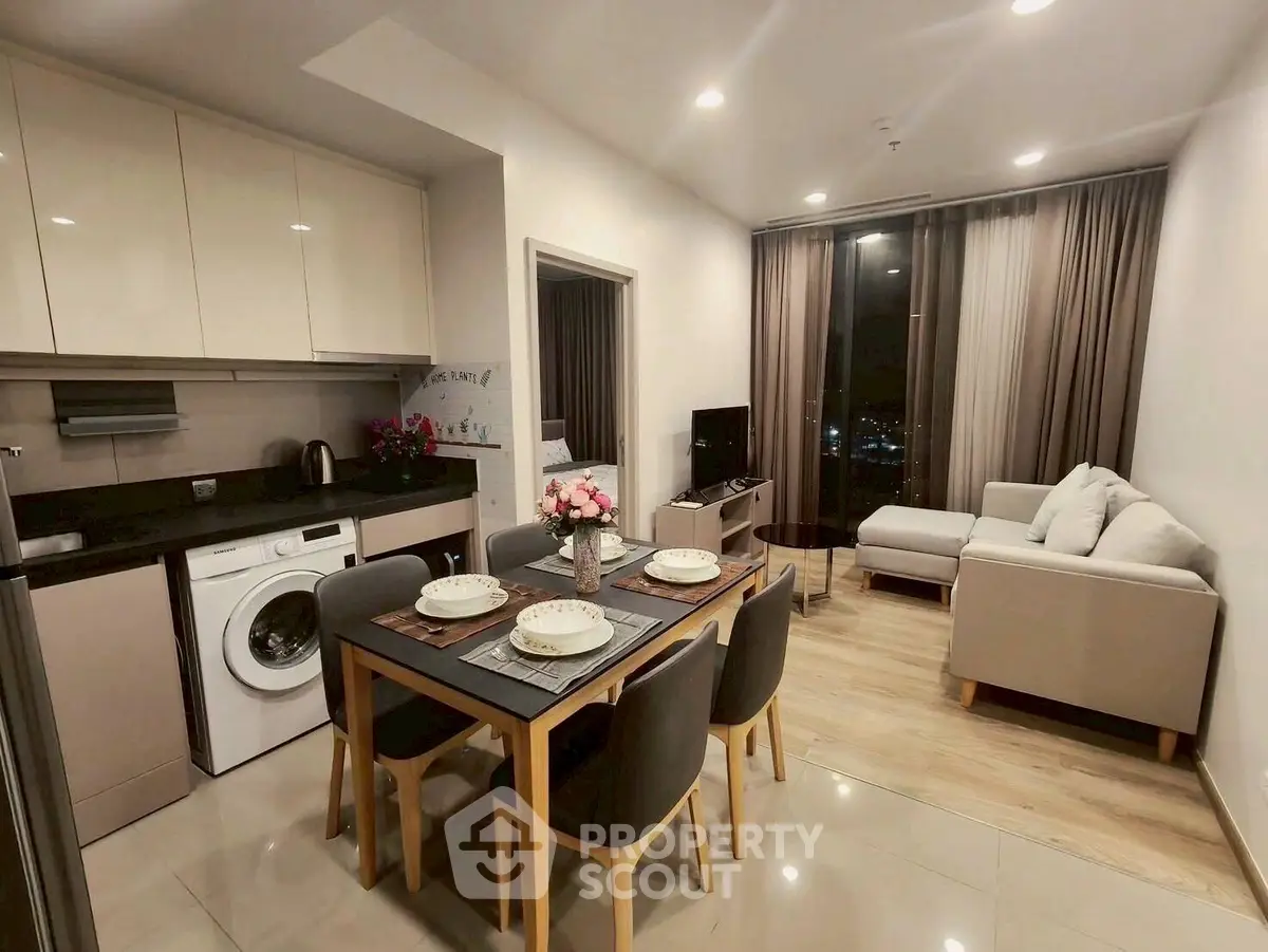 Modern open-plan living room and kitchen with elegant dining area and cozy seating.