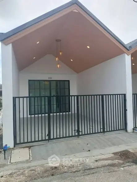 Modern minimalist house exterior with gated entrance and stylish lighting.