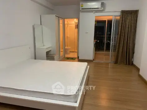 Spacious bedroom with balcony access and ensuite bathroom in modern apartment.