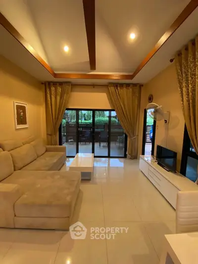 Spacious living room with elegant decor and large windows opening to a lush garden view.