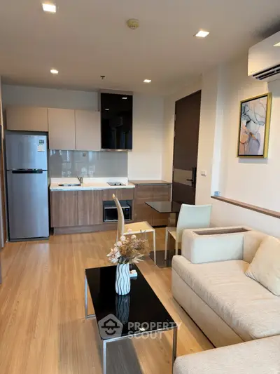 Modern open-layout living room with kitchen, featuring sleek furniture and stylish decor.