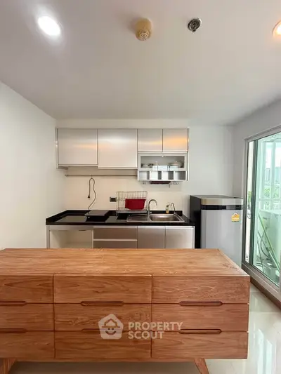 Modern kitchen with sleek cabinetry and compact fridge in a bright apartment