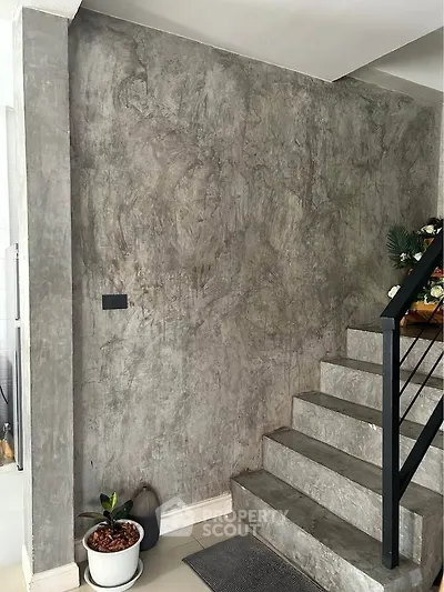Modern concrete staircase with sleek railing and potted plants, perfect for contemporary homes.