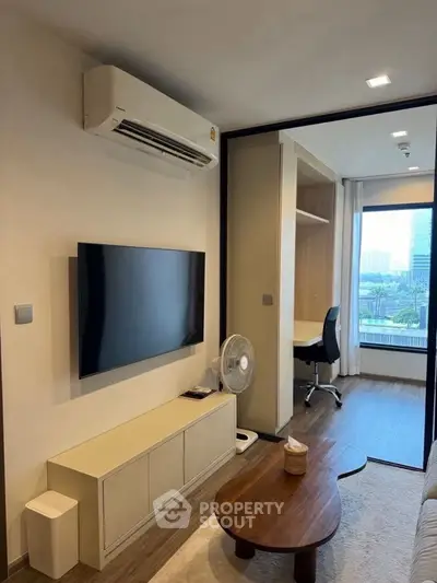 Modern living room with sleek TV setup and study area with city view.