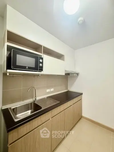 Modern kitchen with sleek cabinetry and built-in microwave in a compact layout.