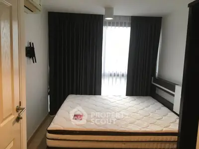 Cozy bedroom with large window and dark curtains, featuring a comfortable mattress and modern decor.