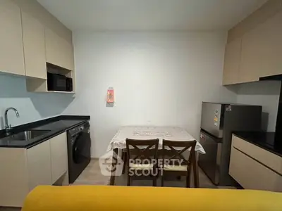 Modern kitchen with sleek cabinetry, dining table, and appliances in a cozy apartment setting.