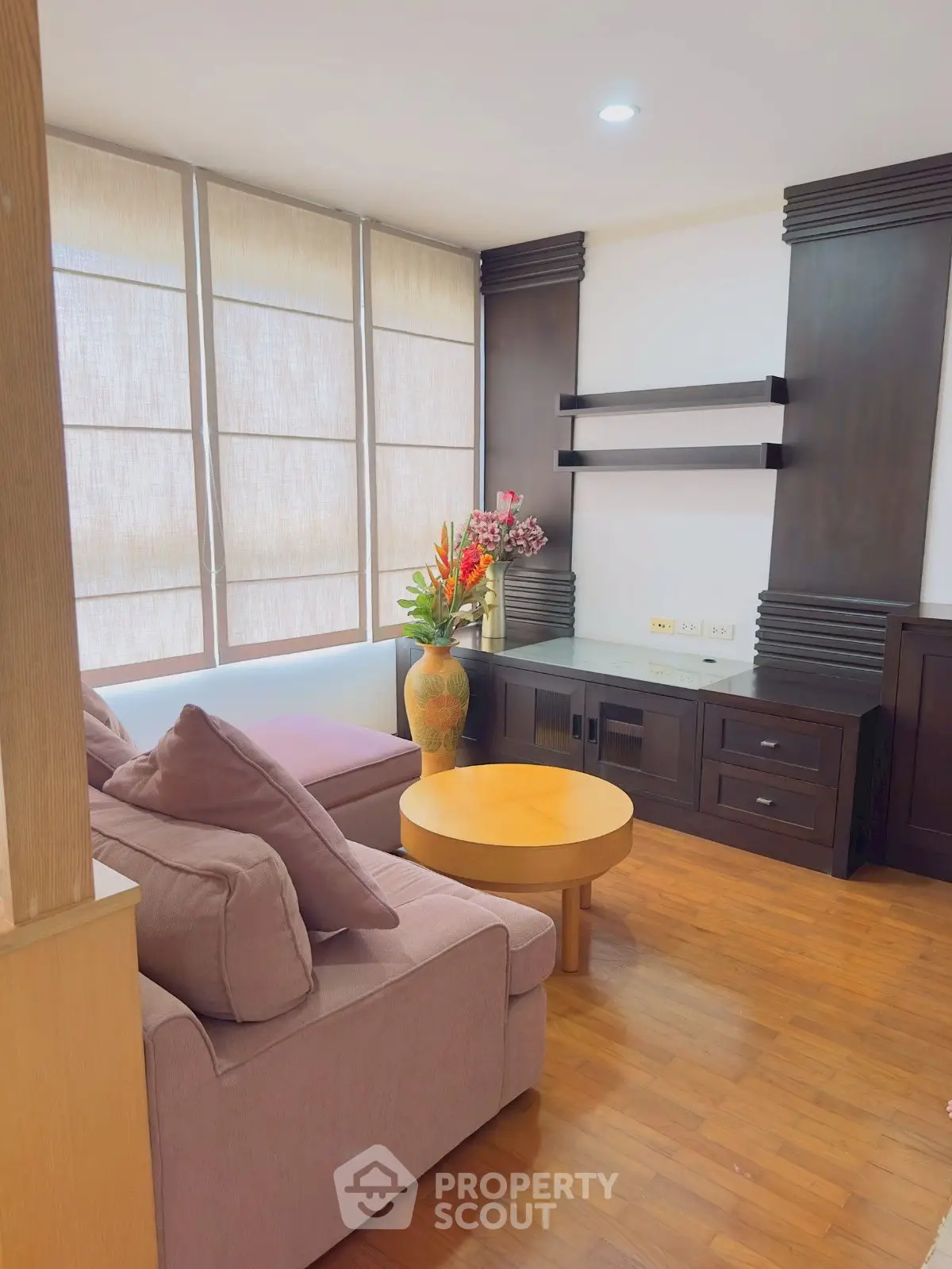 Charming living room with cozy sofa, elegant wooden furniture, and large windows for natural light.