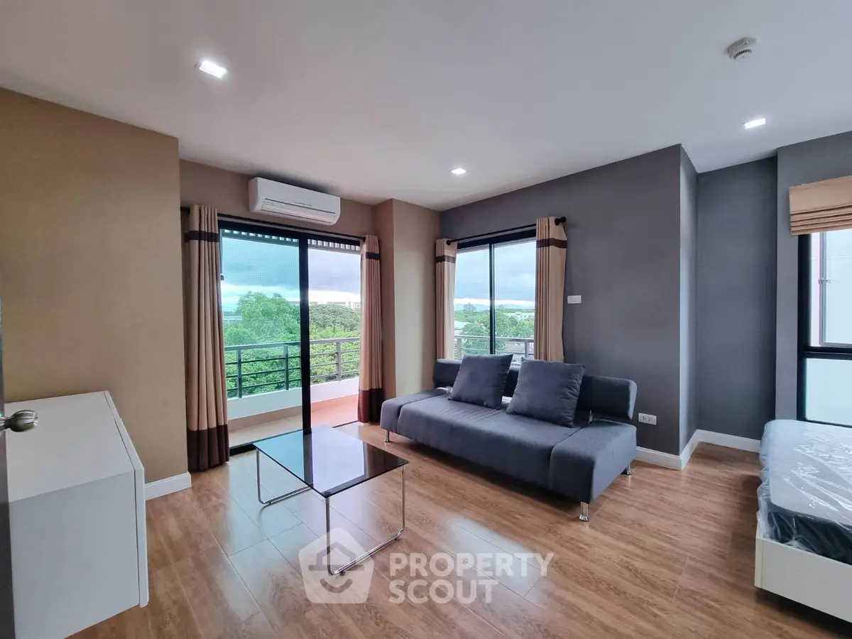 Modern living room with large windows and stylish furniture, offering a serene view of greenery.