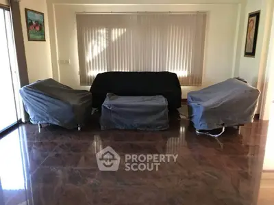 Spacious living room with covered furniture and large windows