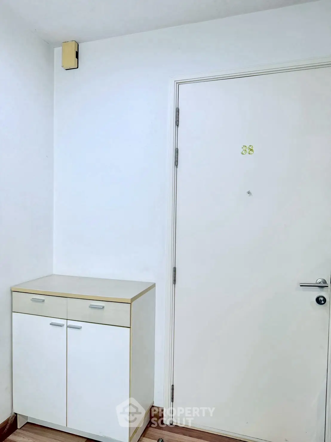 Minimalist entryway with white door and compact storage cabinet