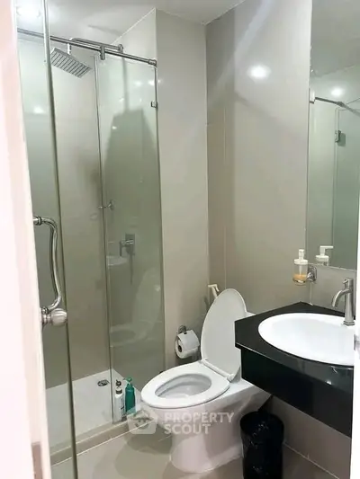 Modern bathroom with glass shower and sleek fixtures in contemporary apartment.