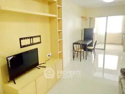 Modern living room with sleek TV setup and dining area in open layout apartment.