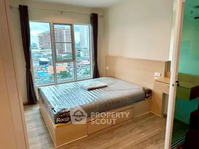 Modern bedroom with large window offering city view, featuring a stylish bed and wooden flooring.