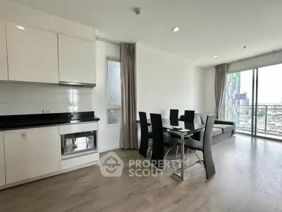 Modern open-plan living room with sleek kitchen and city view, featuring stylish dining area and large windows.
