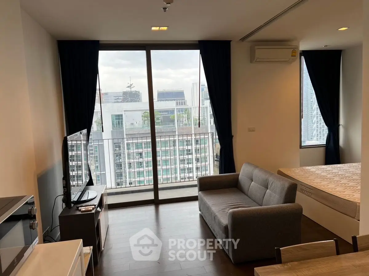 Modern living room with city view, featuring a cozy sofa and large windows.