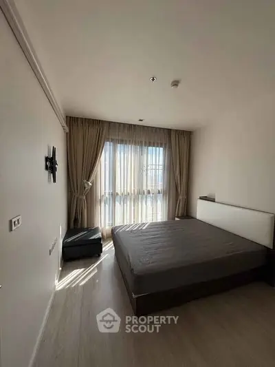 Spacious bedroom with large window and natural light, perfect for relaxation and comfort.