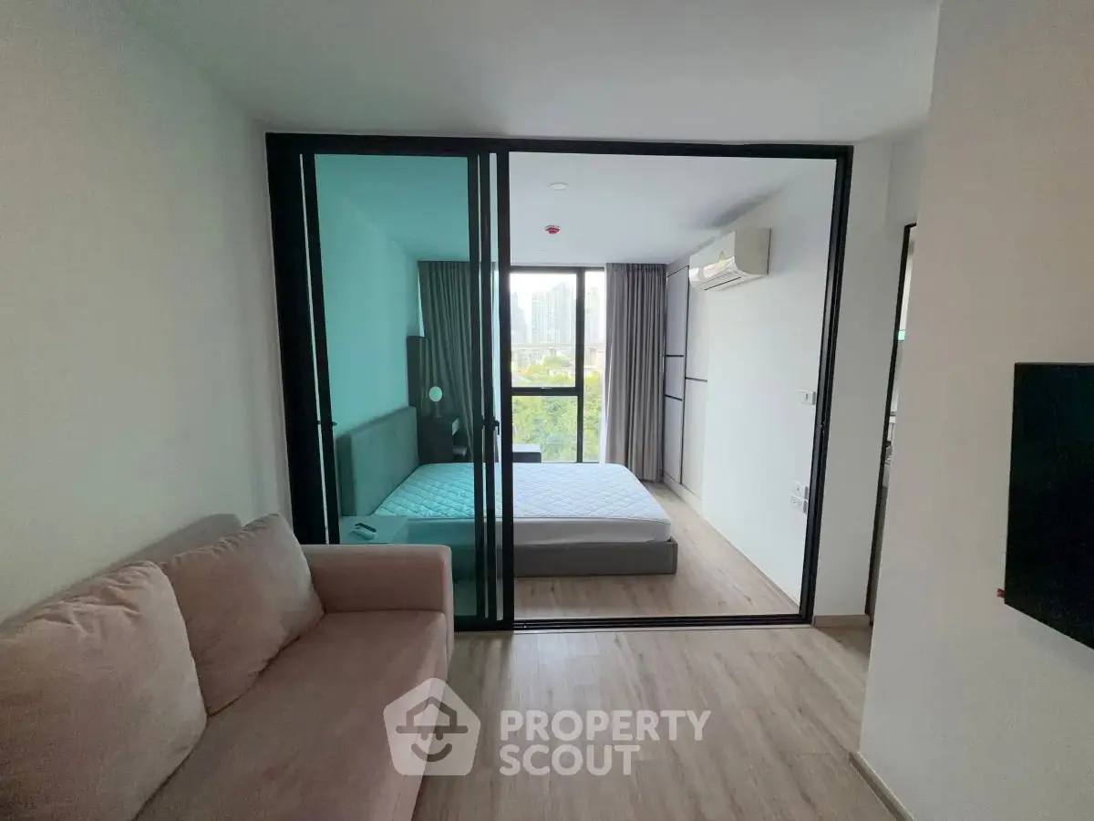 Modern apartment with glass partitioned bedroom and cozy living area, featuring city view.