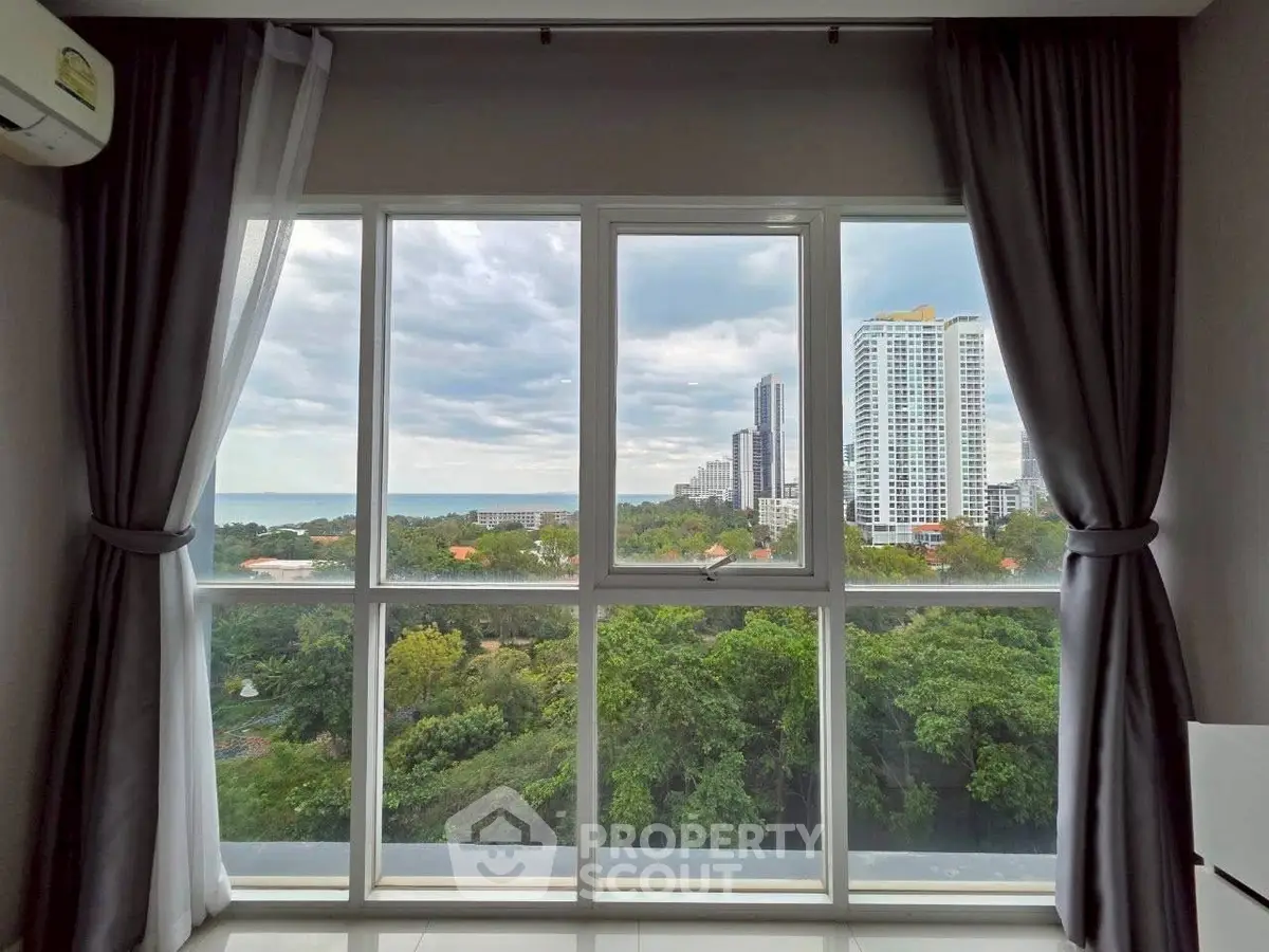 Stunning high-rise view from modern apartment window with lush greenery and cityscape.