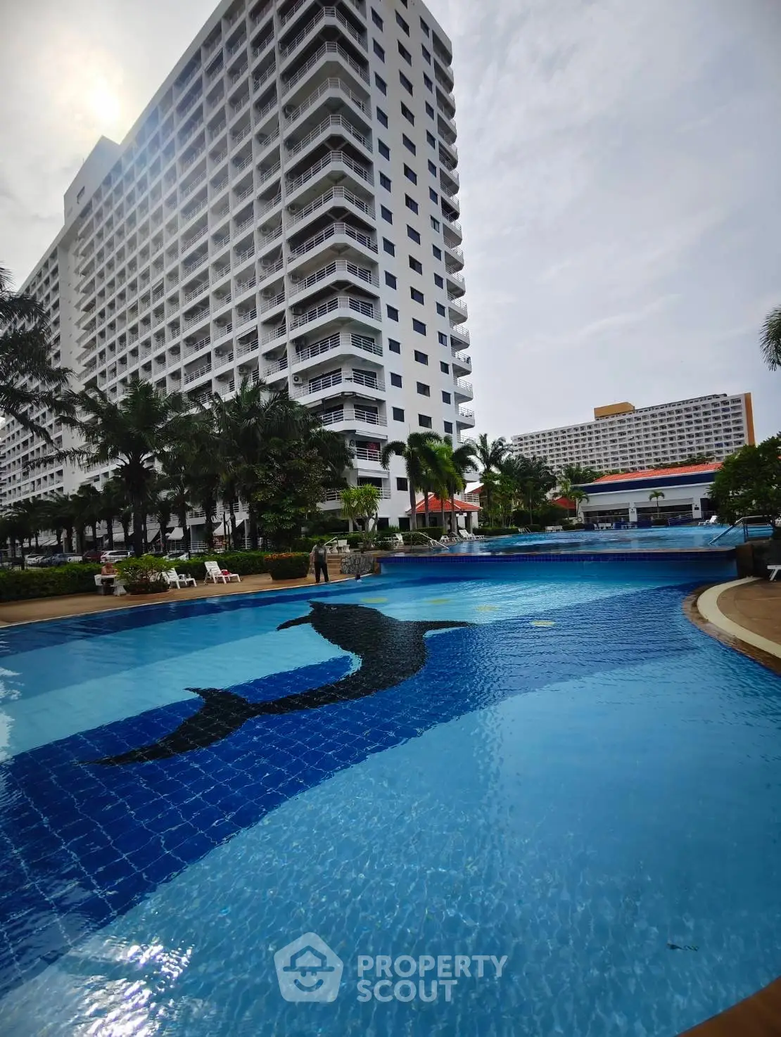 Luxurious high-rise building with stunning poolside view and lush greenery, perfect for modern living.