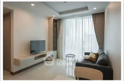 Modern living room with sleek furniture and large window offering natural light.