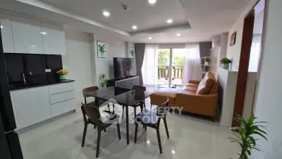 Modern open-layout living room with kitchen, featuring sleek furniture and a balcony view.