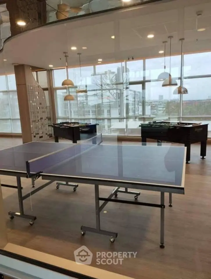 Modern recreational area with table tennis and foosball tables in a bright, spacious room.