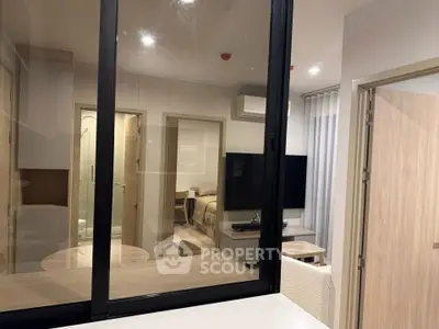 Modern apartment interior with glass partition, cozy bedroom, and stylish living area.