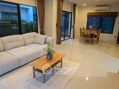 Spacious living room with modern furniture and dining area, large windows, and elegant decor.