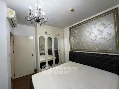 Elegant bedroom with chandelier and stylish wall art in modern apartment