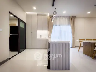 Modern kitchen with sleek design and open layout, featuring a stylish island and elegant dining area.
