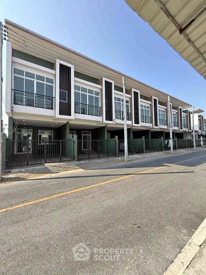Modern townhouse exterior with sleek design and large windows on a sunny day.