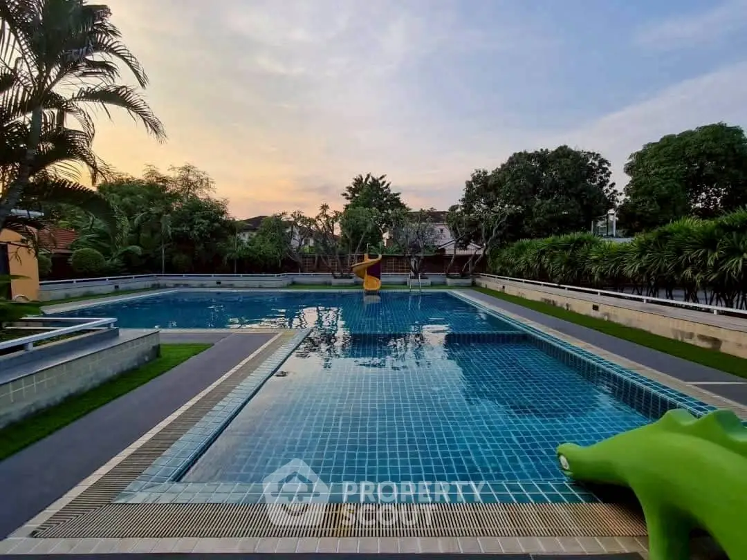 Luxurious residential swimming pool with serene sunset view and lush greenery.