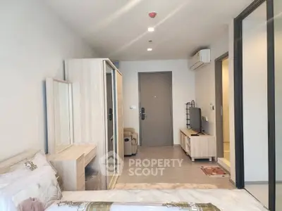 Modern bedroom with sleek furniture and neutral tones, featuring a mirrored wardrobe and air conditioning.