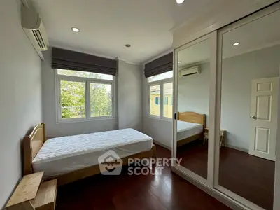 Bright bedroom with large mirrored wardrobe and wooden flooring