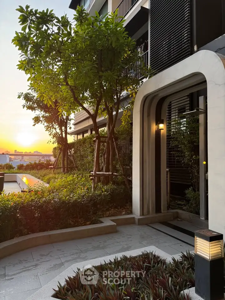 Modern building entrance with lush greenery and sunset view