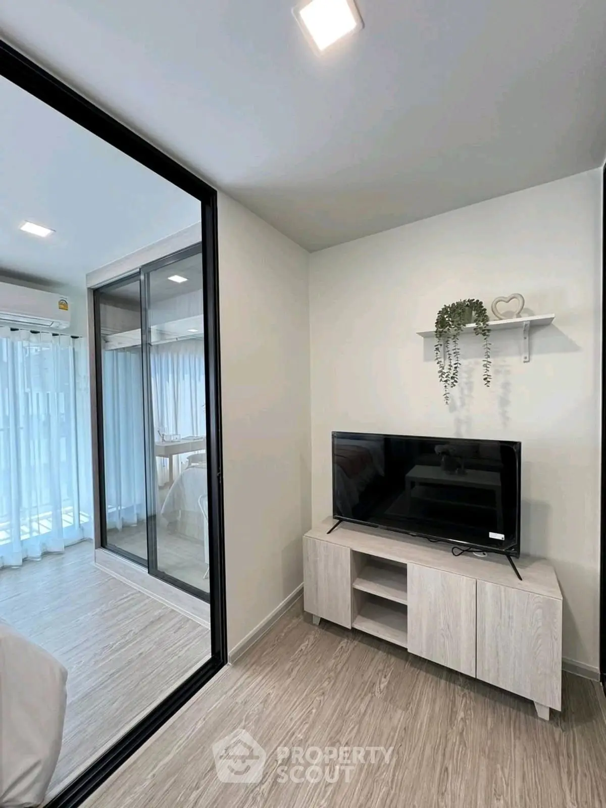 Modern living room with sleek TV stand and glass partition in stylish apartment.