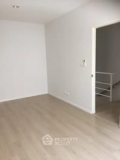 Spacious empty room with light wood flooring and white walls, ideal for customization.