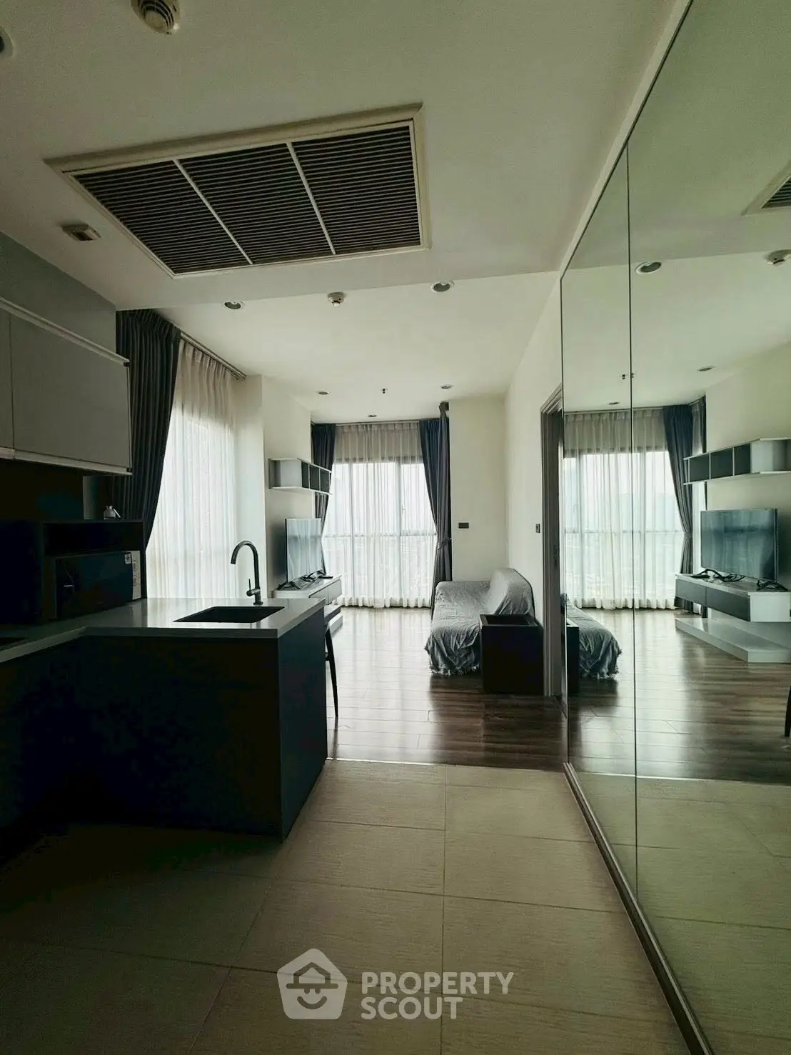 Modern open-layout living room with sleek kitchen and large windows offering natural light.