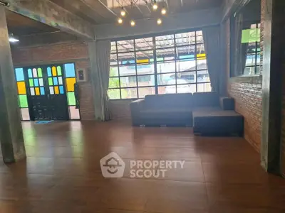 Spacious industrial-style living room with large windows and modern lighting.