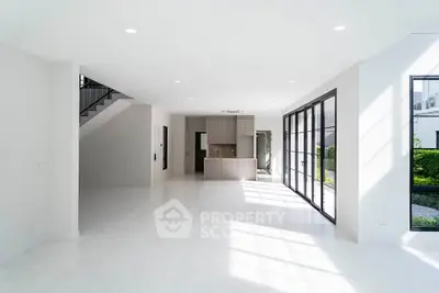 Spacious modern living room with large windows and open kitchen layout, perfect for natural light lovers.