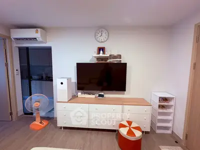 Modern living room with stylish furniture and wall-mounted TV, featuring a sleek air conditioner and vibrant decor.
