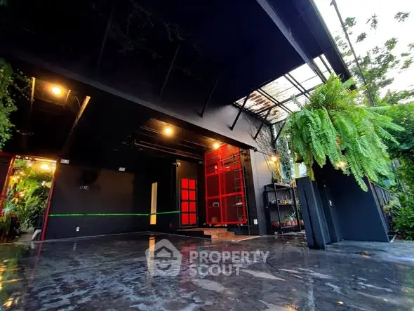 Modern industrial-style exterior with sleek black and red accents and lush greenery.