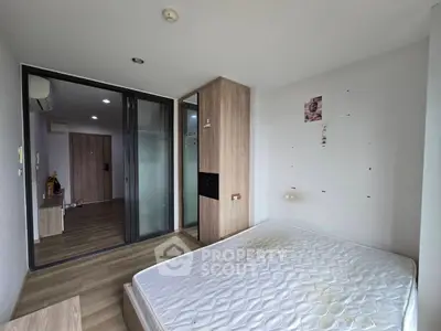 Spacious bedroom with wooden flooring and sliding glass doors in modern apartment.
