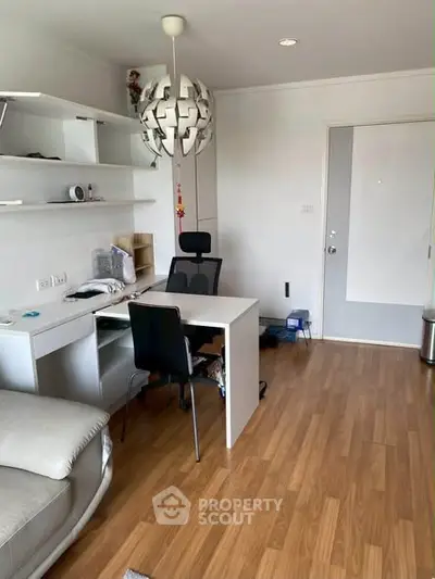 Modern living room with stylish furniture and wooden flooring, featuring a contemporary light fixture and built-in shelves.