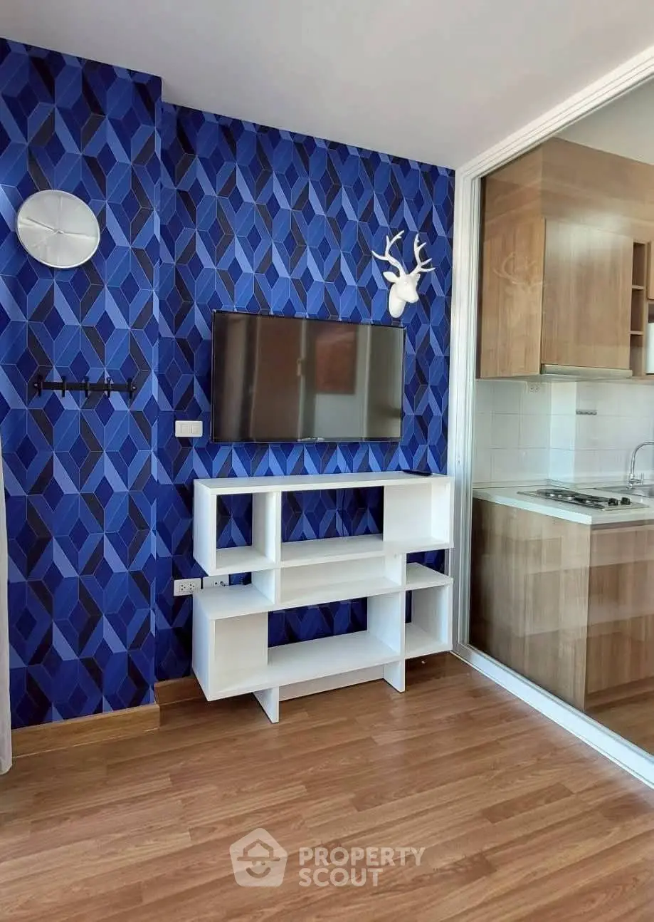 Modern living room with stylish blue geometric wallpaper and open kitchen view.