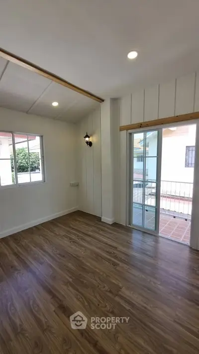 Bright and airy room with wooden flooring and large windows, perfect for a cozy living space.